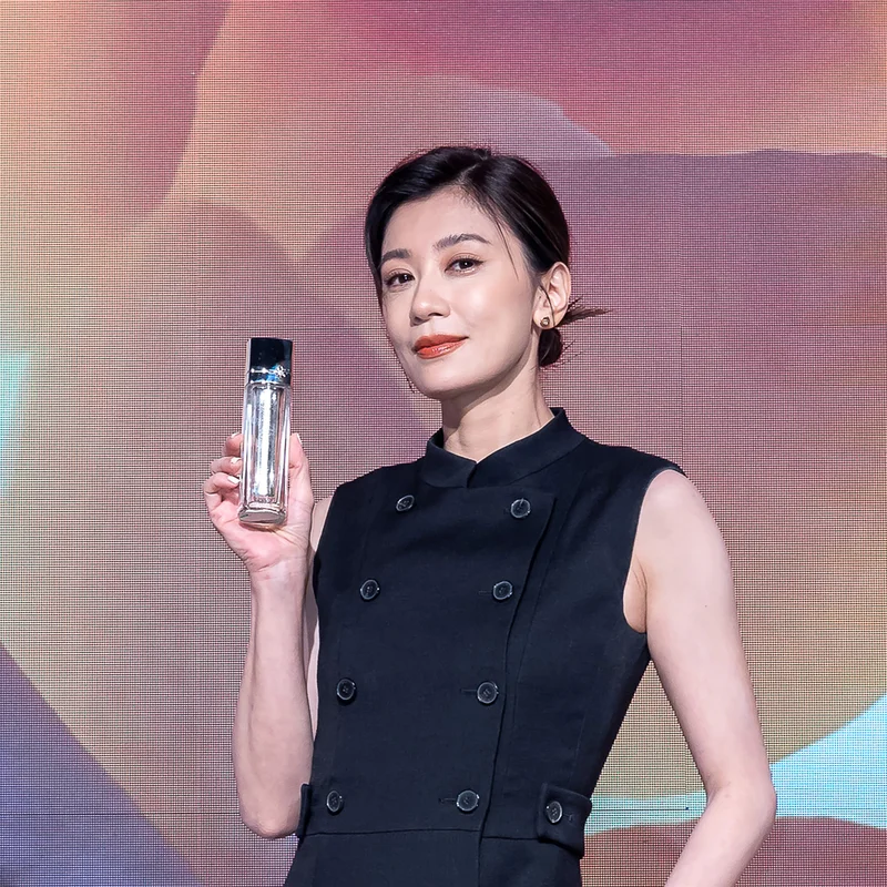 保養大使賈靜雯穿黑色禮服手持迪奧玫瑰源萃，於DIOR PRESTIGE背板前亮相