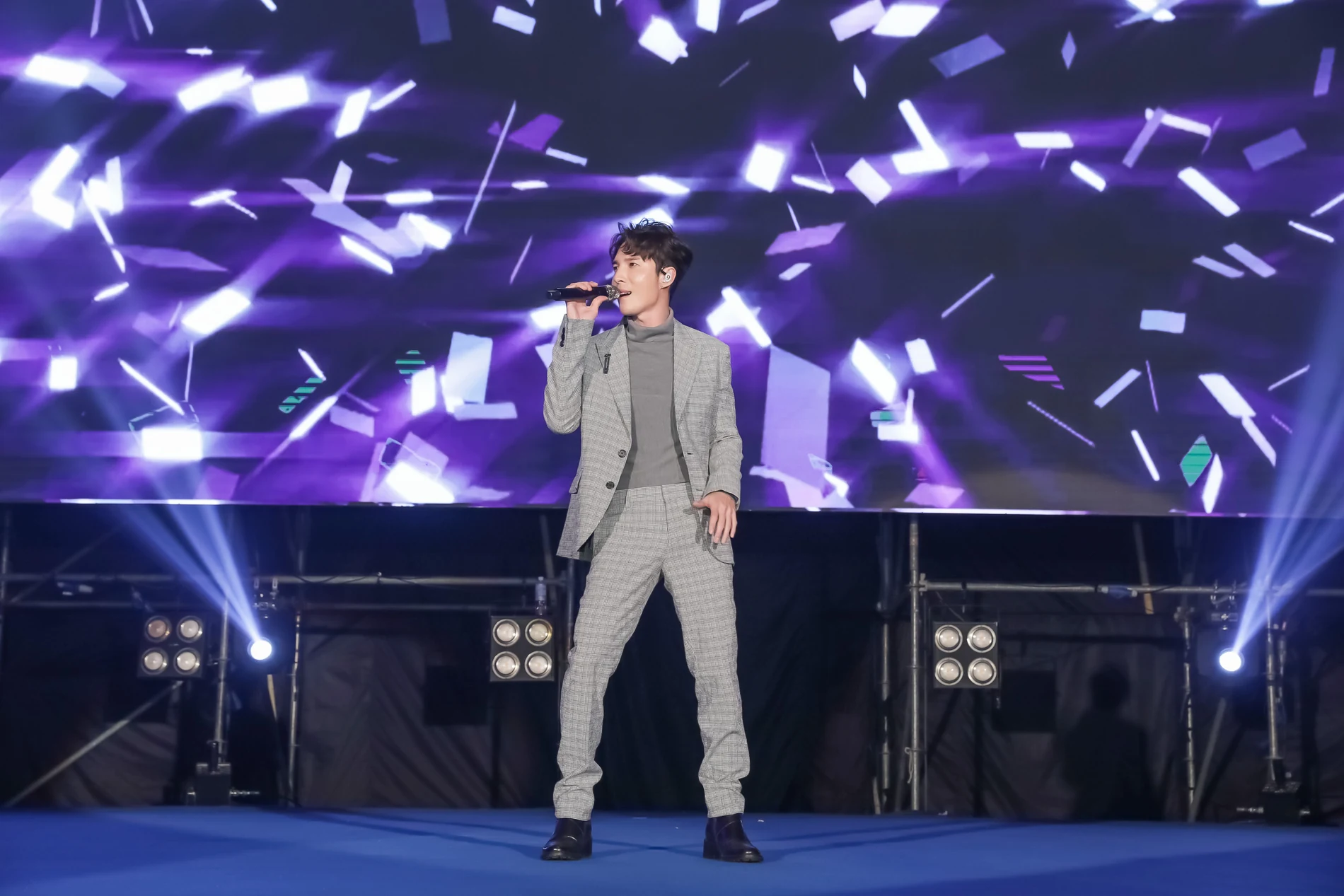 陳勢安穿灰色格紋西裝,在花旗銀行年終晚會紫色光影舞台演唱