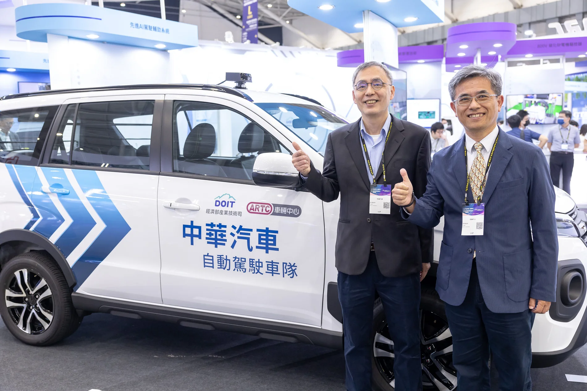 台北國際車用電子展兩位參與者在中華汽車自動駕駛車隊展示車旁合影