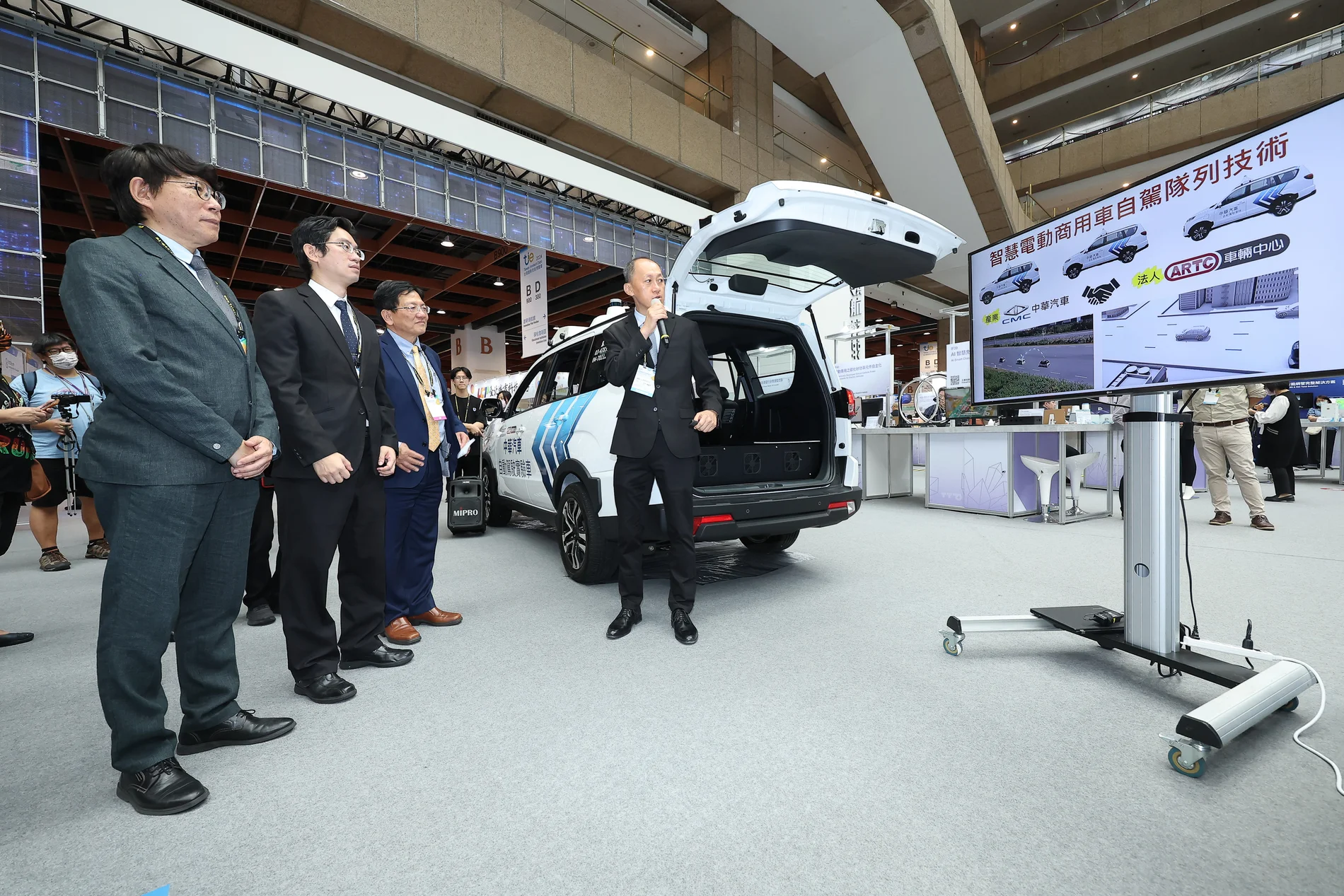 解密科技寶藏展區導覽人員介紹自動駕駛實驗車與技術展示螢幕