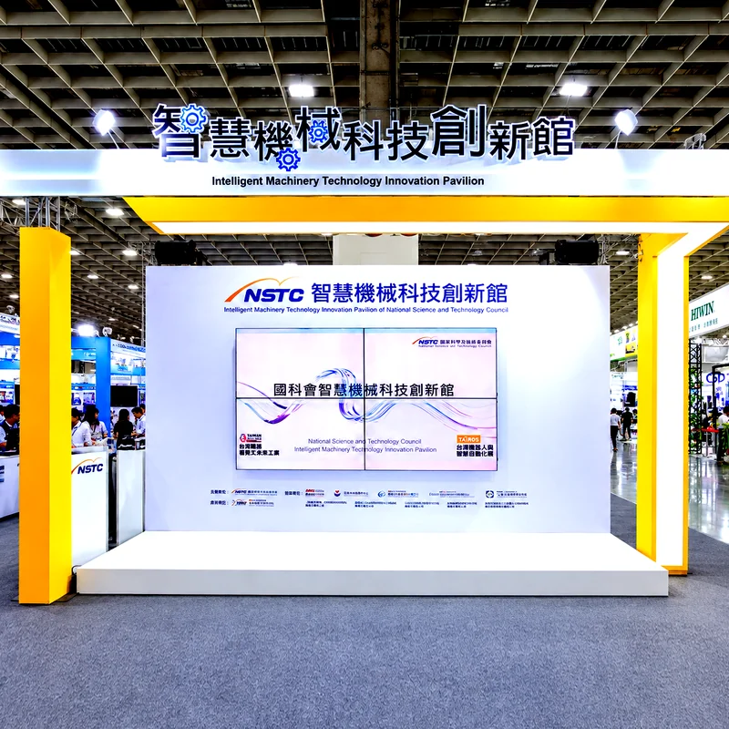 國科會智慧機械科技創新館展區正面全景，黃色框架搭配白色展示背板與科技展示螢幕