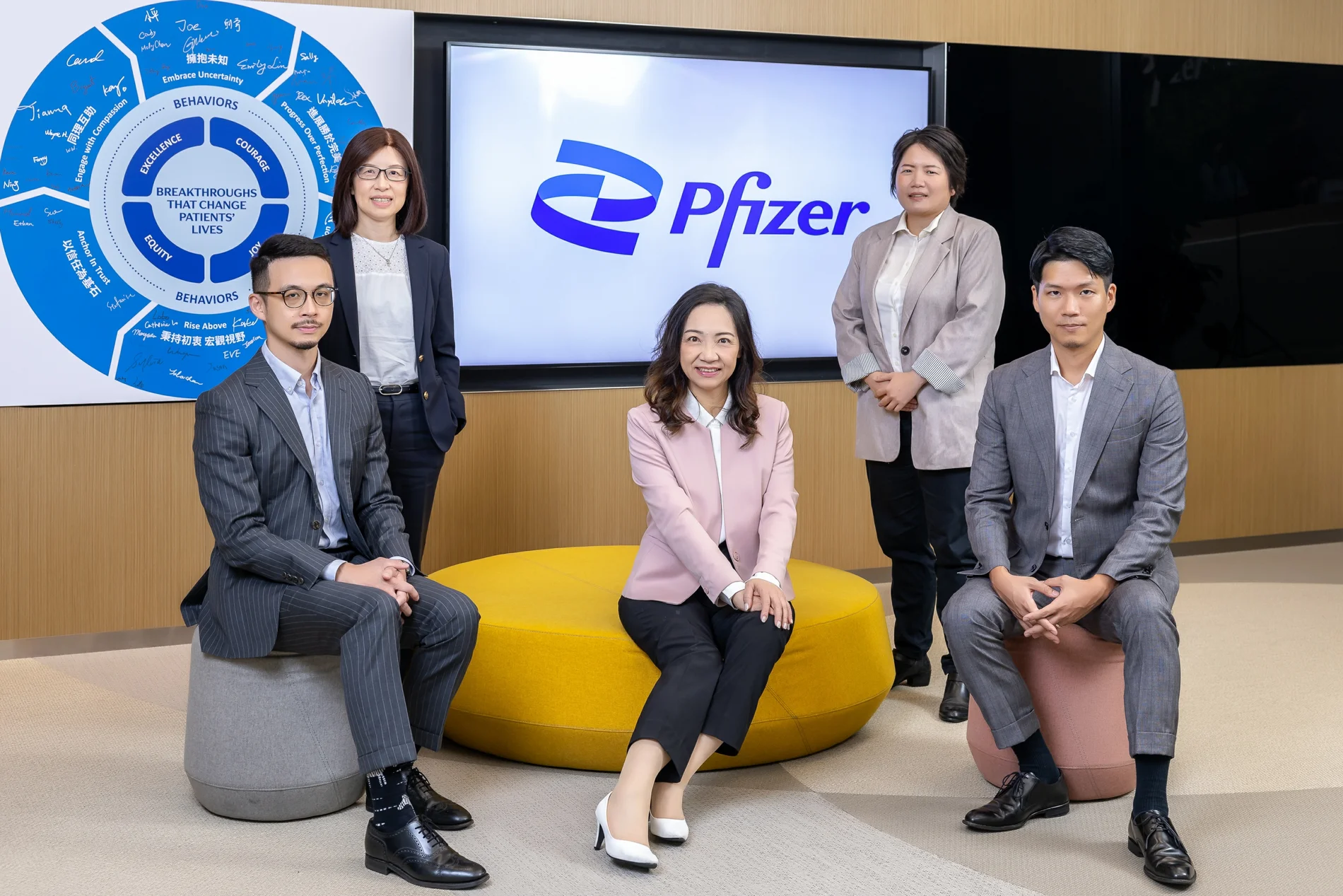 輝瑞大藥廠五位主管在Pfizer品牌螢幕前以站姿與坐姿呈現的團隊形象照
