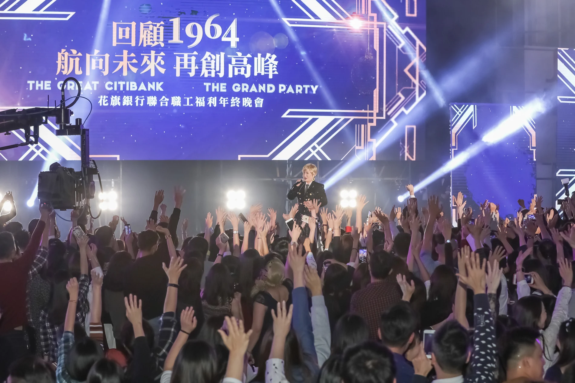 黃小琥在花旗銀行年終晚會舞台演唱,台前觀眾舉手呼應